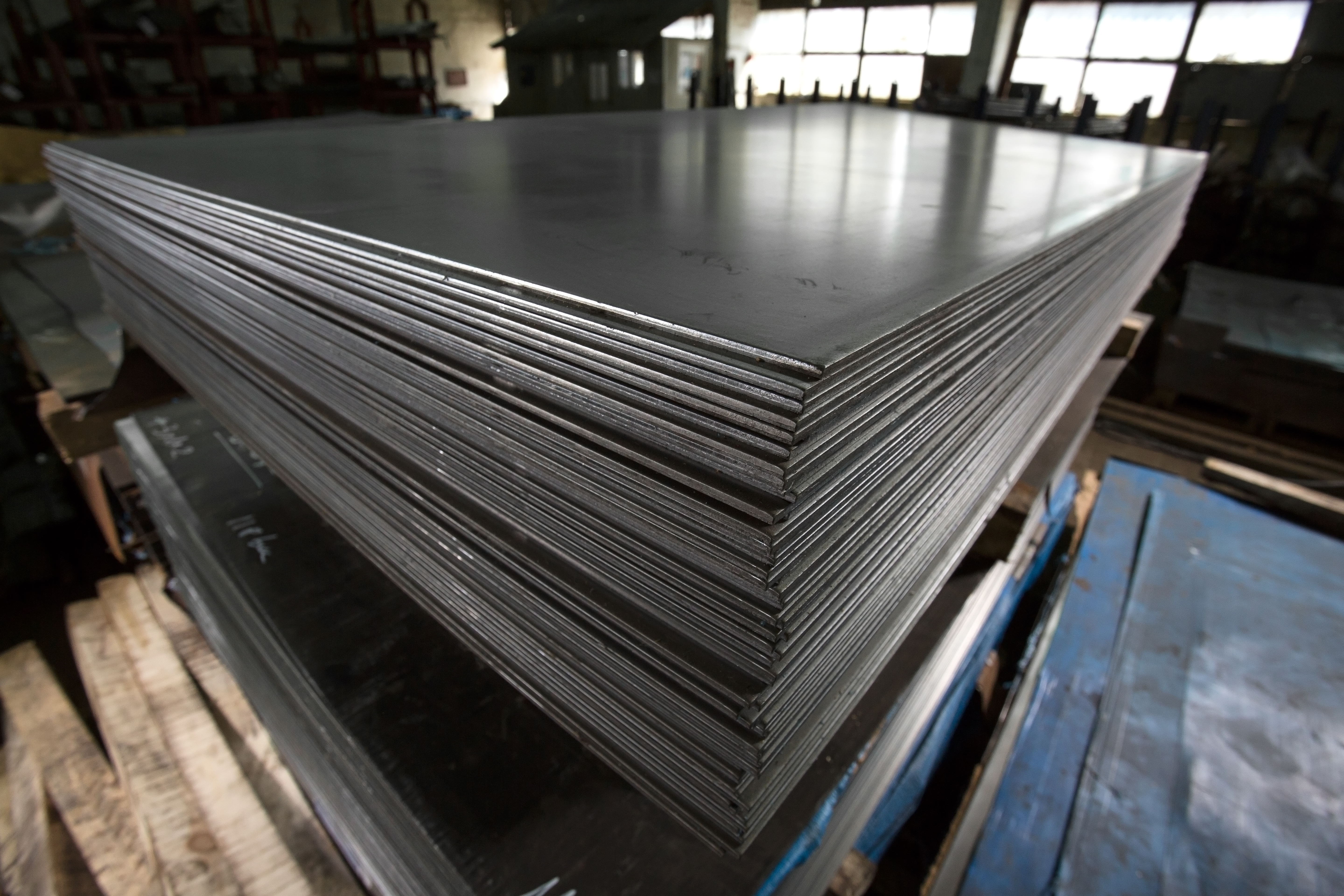 Stainless steel pipes, bars and sheets of metal,  deposited in stacks in a industrial warehouse